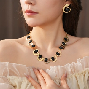 Détail d'une parure collier et boucles d'oreilles dorées avec pierres ovales noires