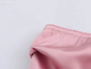 Détail rapproché de la texture du satin rose et des coutures précises du pantalon large