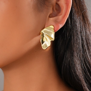 Close-up of golden irregular wavy stud earrings with molten lava texture on model