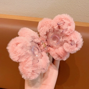Cute pink plush chrysanthemum hair claw clip for winter styling in a hand-held view