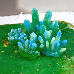 Primer plano de moldes de resina de cristal con degradado azul-verde y purpurina dorada