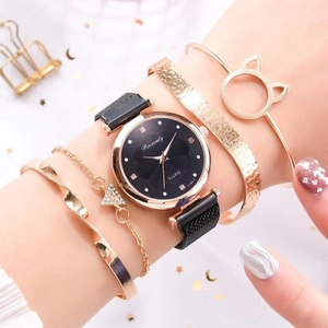 Close-up of rose gold watch set with black mesh strap and matching bracelets on wrist