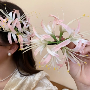Detailed close-up of pink and white gradient Lycoris flower hair clip on hair