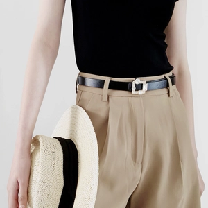 Detail of slim black leather belt with rhinestone buckle on high waist khaki trousers