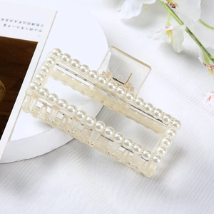 Detail of elegant pearl-encrusted transparent hair claw clip on white display stand