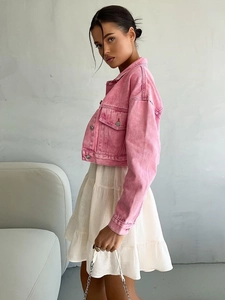Pink cropped denim jacket paired with a white tiered cotton mini dress on a model