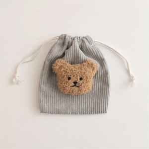 Detail of grey corduroy drawstring pouch featuring a plush brown bear applique