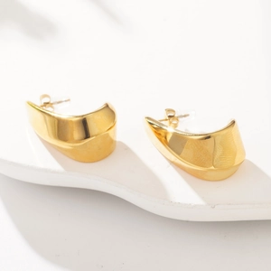 Close-up of gold C-shaped chunky hoop earrings on a white artistic display stand