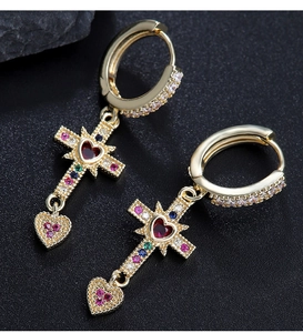 Macro shot of gold cross earrings with red heart gems and colorful zircon inlays