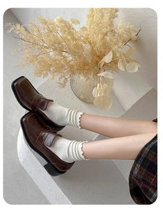 Detail of white ruffle socks paired with brown leather loafers for an elegant fall look