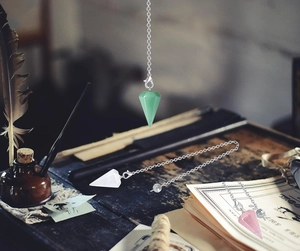 Three conical natural stone crystal pendants with silver metal chains on vintage desk
