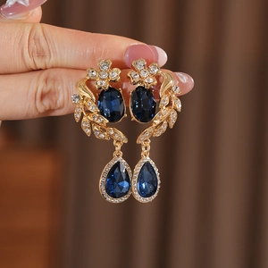 Gros plan détaillé de boucles d'oreilles vintage dorées avec gemmes bleues et feuilles