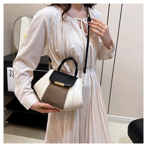 Detail of color-block leather handbag showing top handle and adjustable shoulder strap