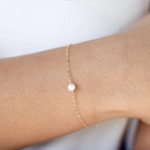 Makroaufnahme eines minimalistischen Goldketten-Armbands mit einer glänzenden Perle