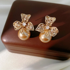 Gros plan de boucles d'oreilles fleurs dorées avec perles et zircons sur un coffret