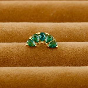 Close-up of five green pear-cut stones in a golden prong setting on a cartilage stud