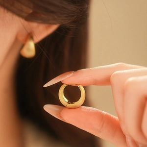 Close-up of golden brushed metal hoop earrings with a textured matte finish