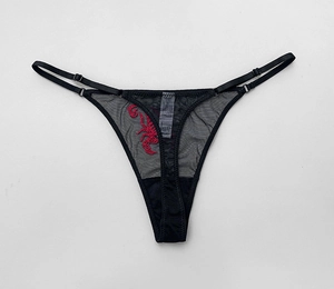 Detailed close-up of black mesh thong featuring intricate red scorpion embroidery detail