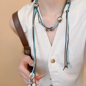 Detail of bohemian suede necklace with silver metal discs and blue leather cords