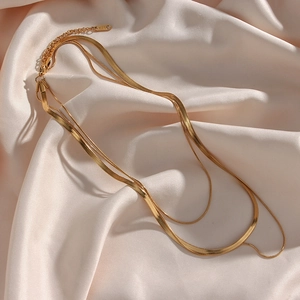Macro detail of 18K gold-plated double-layered snake chain necklace on silk