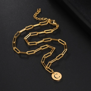 Detail of gold-plated paperclip chain necklace with a round initial C letter pendant