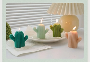 Quatre bougies parfumées en forme de cactus vert et rose avec des textures réalistes sur un plateau