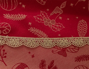 Macro shot of red Christmas jacquard fabric with gold pine cones and lace trim