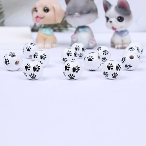 Close-up of white wooden beads with black paw prints for DIY jewelry making