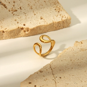 Detail eines vergoldeten Edelstahlrings mit Lava-Design auf beigem Travertinstein