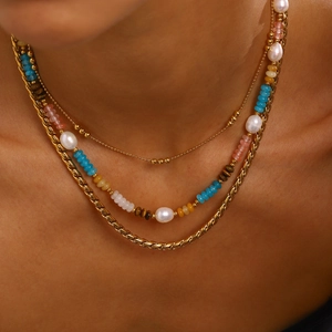 Detail of layered gold necklace with colorful beads, pearls and snake chain