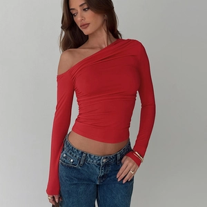 Détail du plissé à la taille et du tissu rouge sur le haut à une épaule asymétrique