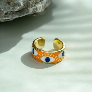 Detailed close-up of 18K gold-plated evil eye ring with vibrant orange enamel inlay