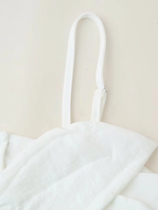 Gros plan détaillé des fines bretelles et de la texture tissée d'une robe d'été blanche
