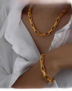 Dettaglio del set collana e bracciale a maglie rettangolari dorate su camicia bianca