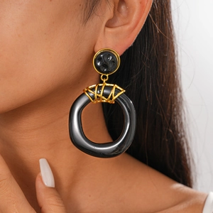 Close-up of black resin crumpled geometric earring with gold metal accent on model