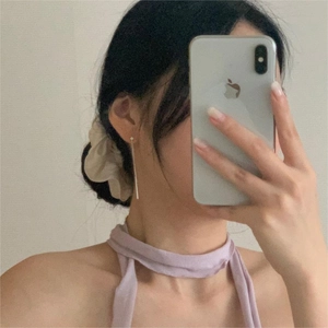 Detailed view of minimalist long silver tassel earrings worn in a lifestyle setting
