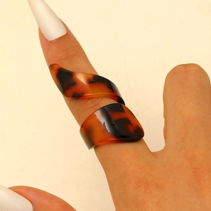 Macro shot of tortoiseshell resin ring with brown spiral geometric pattern on hand