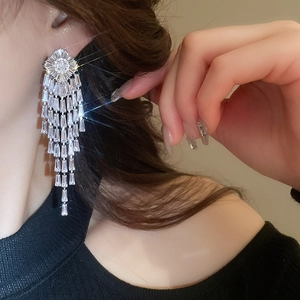 Close-up of dangling silver rhinestone tassel earrings with emerald cut cubic zirconia