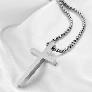 Vue détaillée du pendentif croix en argent poli sur un tissu en soie blanche plissée