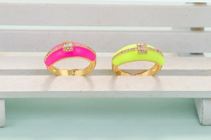 Detail of colorful enamel rings with rectangular zircons on a white miniature bench