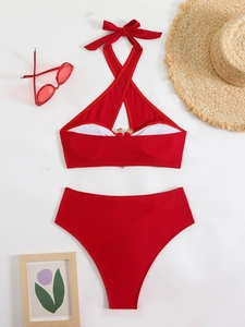 Flat lay of red bikini set with halter top and high-waisted bottoms on beach accessories