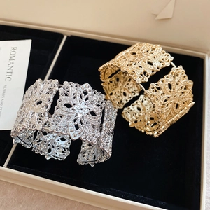Détail des bracelets ajourés dorés et argentés dans un écrin de bijoux en velours noir