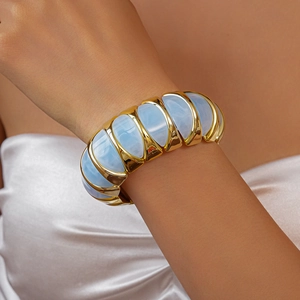 Close-up of wide acrylic stretch bracelet with gold metal frame and blue marble texture
