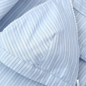 Close-up of light blue striped cotton shirt with delicate lace trim on the hem