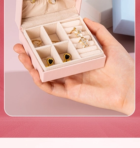 Pink portable mini jewelry box with ring slots held by hand showing compact size