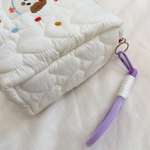 Detailed close-up of heart-quilted fabric and purple braided handle on dog makeup bag