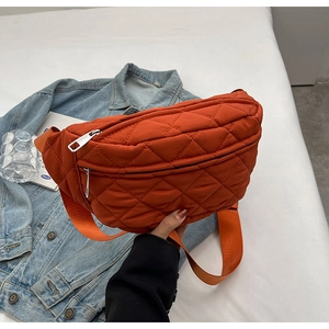 Close-up of orange quilted crossbody bag with adjustable strap and silver zipper detail