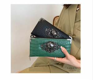 Detail of crocodile pattern leather purse featuring a metal skull and silver corners