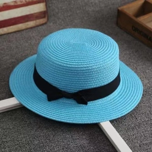 Detailed top view of light blue straw sun hat with black ribbon bow on grey background
