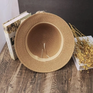 Foldable straw sun hat for women with ribbon on rustic wooden desk background